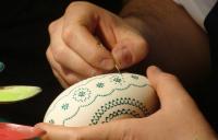 A close up photo of hands painting an Easter egg