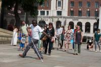Photo of man dancing with a white cane followed by audience