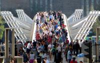 Photo of people crossing The Millennium Bridge in front of Tate Modern 