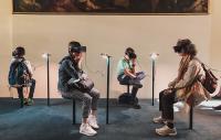 four people sitting in a gallery wearing virtual reality headsets