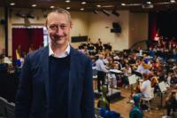 Evan Dawson, incoming Chief Executive, National Youth Arts Wales. He is photographed in front of an orchestra practising.