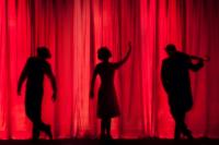 Silhouettes of three people on a stage curtain