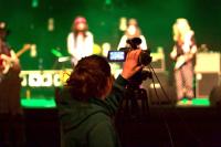 A young person recording a music performance using video equipment