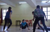A theatre workshop in which students rush at a young person seated on the ground
