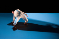 A dancer leaning back on a stage lit in vivid blue