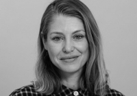 Lilli Geissendorfer, Director of Jerwood Arts. Black and white image of Geissendorfer. She has short, light hair and big eyes/lips. She is wearing a chequered shirt.