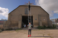 A circus performer balances on top of a ladder in front of the Ice House in Great Yarmouth