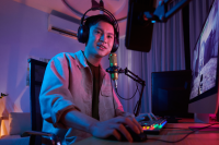 voice over artist working in a studio. image depicts a man wearing headphones, speaking into a microphone while doing work on his computer
