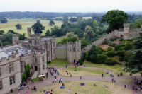 Exterior of part of Warwick Castle. The photo is an aerial view of the castle walls, showing members of the public in the castle grounds