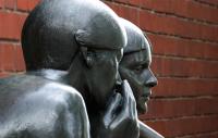 A photo of a statue of a person whispering into someone's ear
