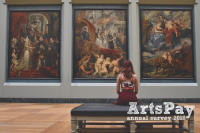 A woman sitting in front of paintings in a gallery
