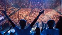 Photo of people at concert with arms outstretched