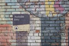 Accessible entrance sign on a brick wall