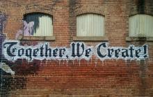 Photo of a wall graffitied with the words "Together We Create!"