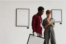 Two people in a gallery looking at a tablet