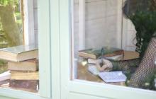 a female writing at a desk behind a glass door
