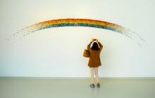 Woman taking a photo of an art installing depicting a rainbow