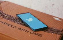 Twitter loading screen on a phone resting on a cardboard box