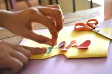 Young person cuts out hearts and sticks to card