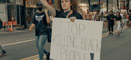 woman marching with banner 'stop killing black people'