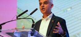 Sadiq Khan speaking at an event wearing a white collared shirt and dark suit jacket