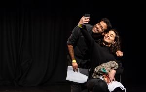 Two actors perform on stage, smiling taking a selfie