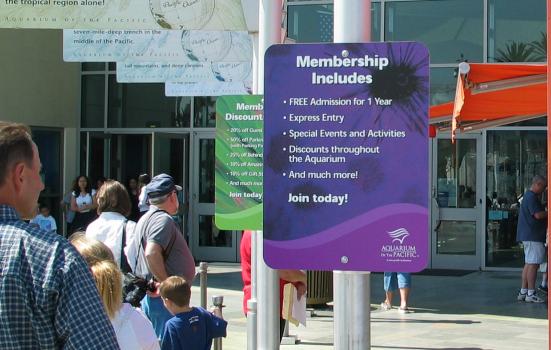 People queuing for an aquarium amongst membership signs