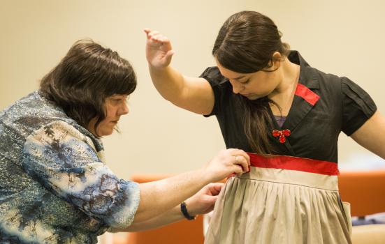 Assistant stage manager Teresa Morrow applies finishing touches to a costume worn by actor Sara Billeaux.