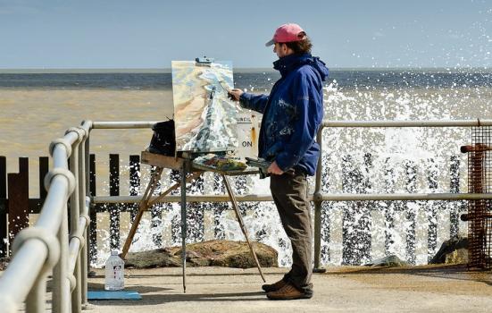 Photo of a man painting by the sea