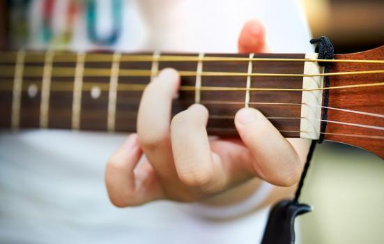 A close up of a person's hand playing the guitar