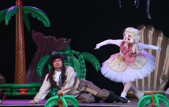 A performance of a pantomime. A man dressed as a pirate lies on the floor with a woman in a tutu dancing beside him