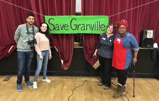 Four people standing on stage in front of a sign saying 'Save Granville'