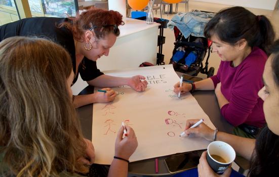 Group of women drawing stickmen around a table