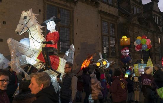 A crowd of people on a street holding illuminated paper sculptures
