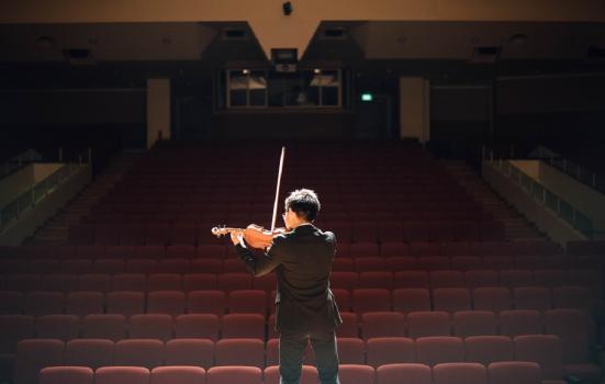 Performer playing violin to an empty theatre