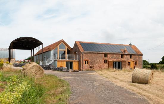 Clayhill Arts building. A converted barn in a rural landscape with hay bales in the foreground