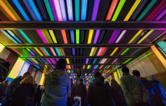 Crowed looking at coloured lights on a tunnel