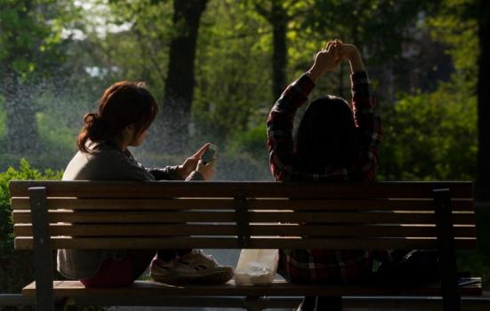 Photo of people on phones on a bench