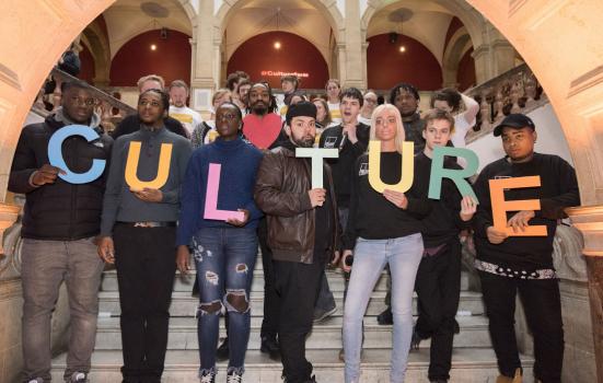 Photo of a group of people holding individual letters to spell out "cuture"