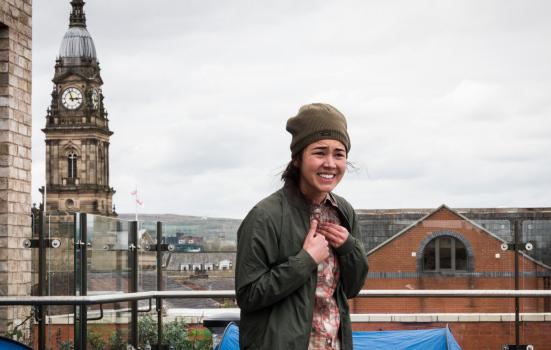 Photo of female actor on rooftop with church spire behind
