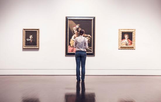 a women looks at paintings in galleries
