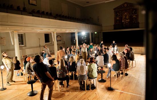 a group of people sitting and standing whilst singing in a hall