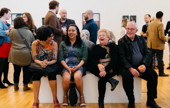 People sitting on a bench in the middle of an art gallery