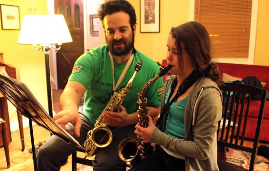 Man teaching a young girl to play saxophone
