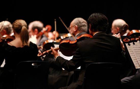 A photo of violinists playing in an orchestra