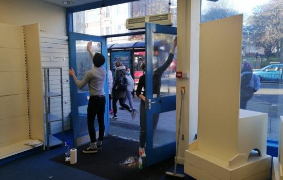Two volunteers helping paint a shop's fornt doors