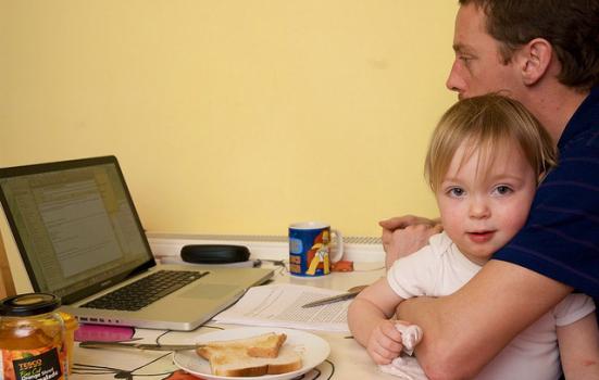 Photo of a man working from home with a child
