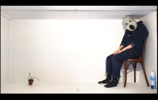Man in a mask sitting in a low, celingless room