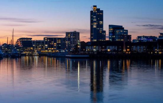Southampton skyline in the evening. The buildings are reflected on body of water.