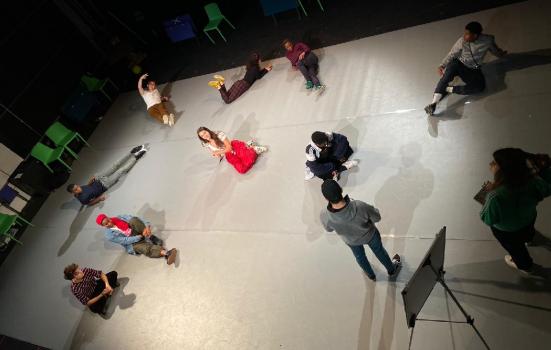 A group of performers lying on stage distanced from one another
